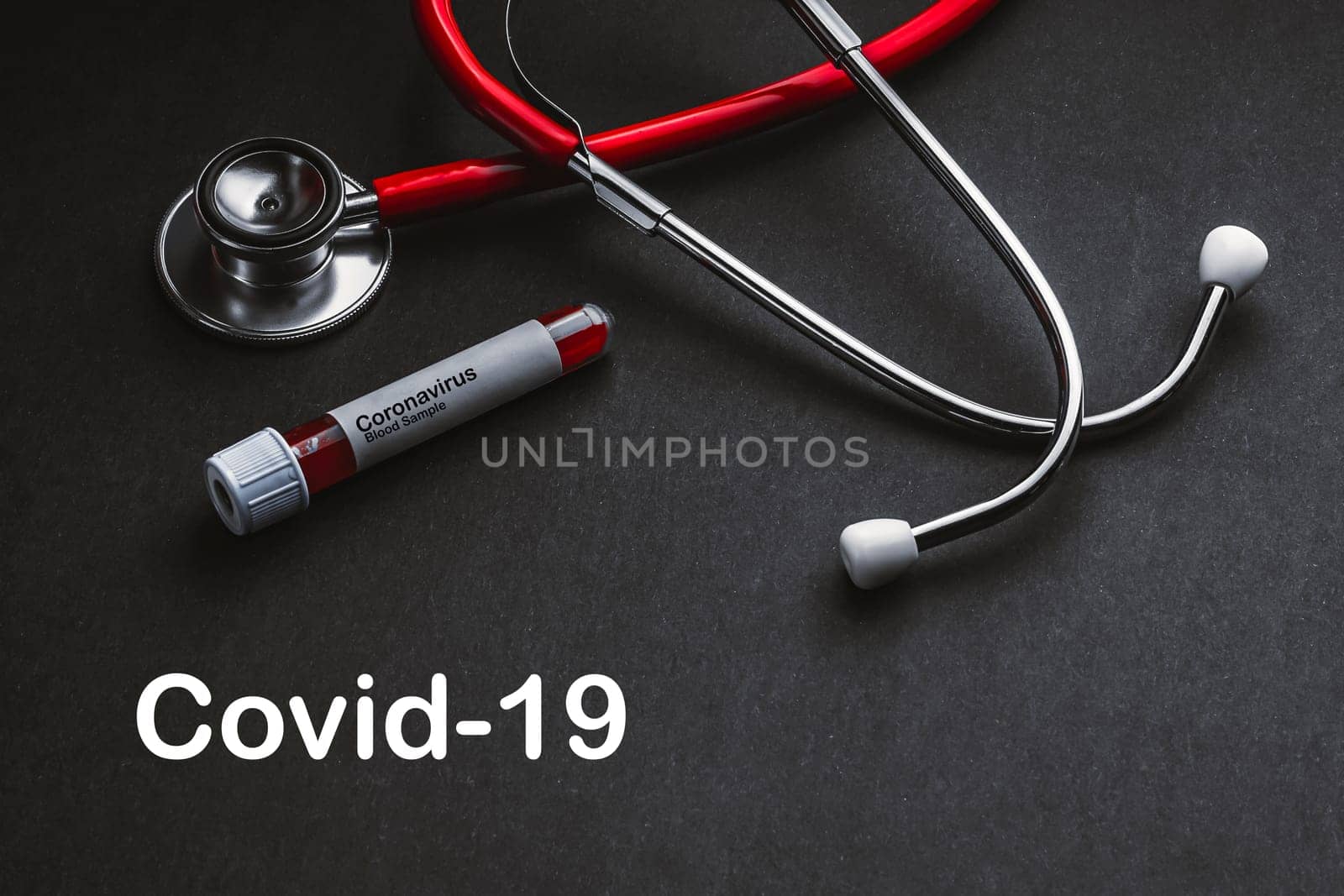 COVID-19  text with stethoscope and blood sample vacuum tube on black background. Covid or Coronavirus Concept