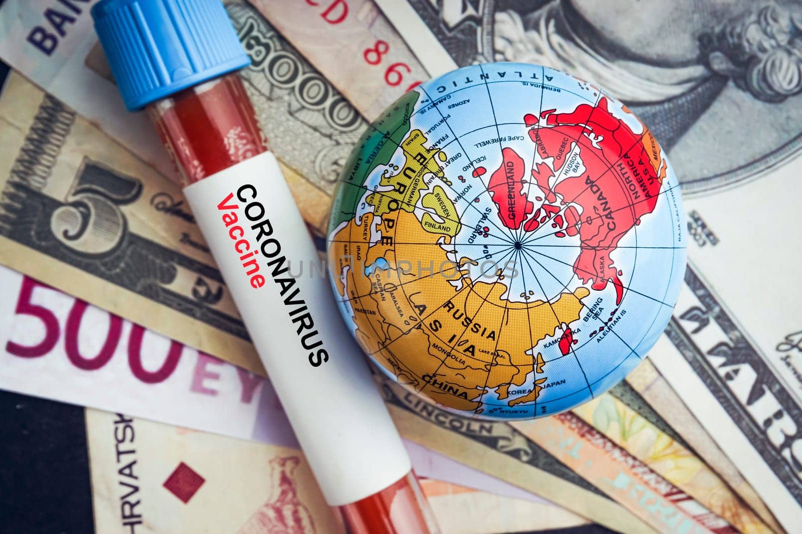 CORONAVIRUS VACCINE text with currency banknotes, world globe and blood test vacuum tube on black background. Covid-19 or Coronavirus Concept