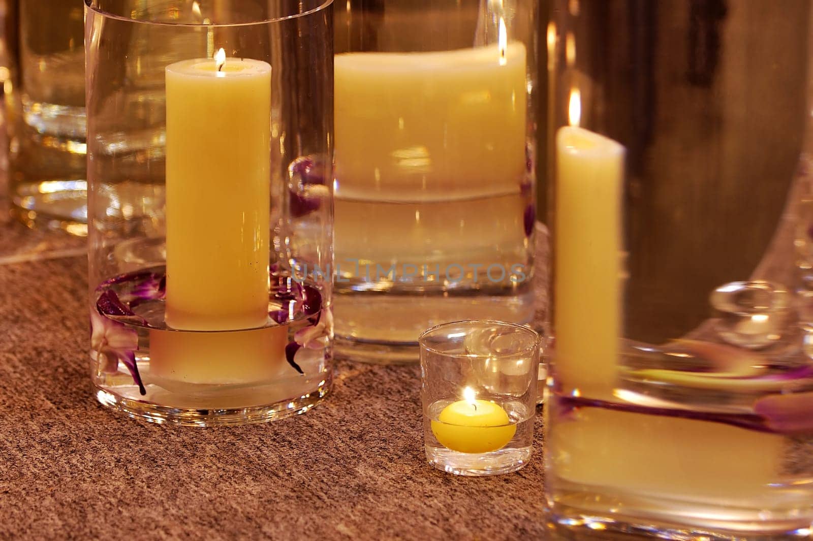 Shot of burning candles with different vases and glasses as candle holders