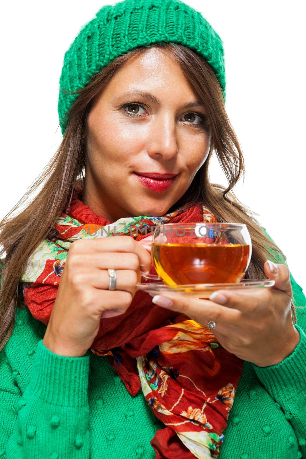 Attractive woman with green wool hat in winter drinks a cup of tea isolated against a white background