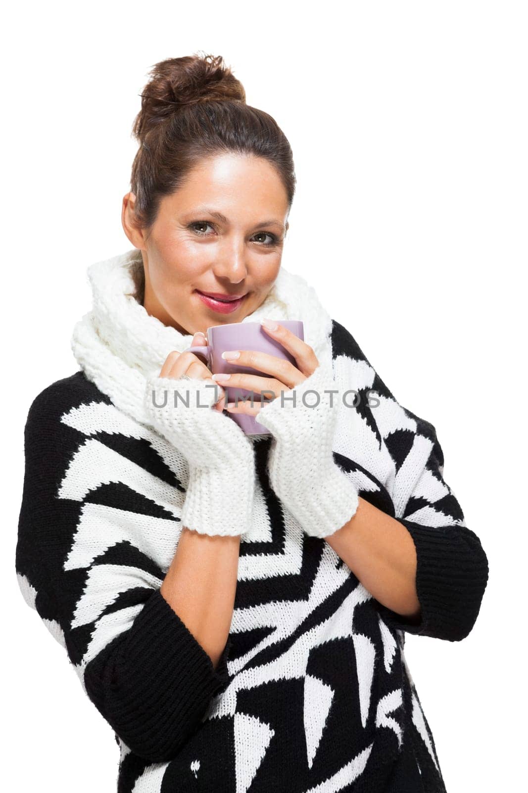 Young attractive woman with black white wool sweater drinks a cup of coffee or tea and warms her hands at the cup isolated on white background