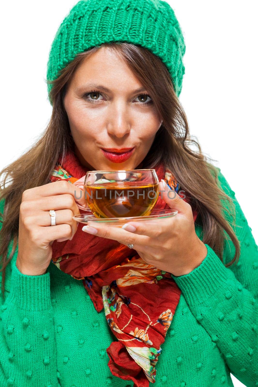 Attractive woman with green wool hat in winter drinks a cup of tea isolated against a white background