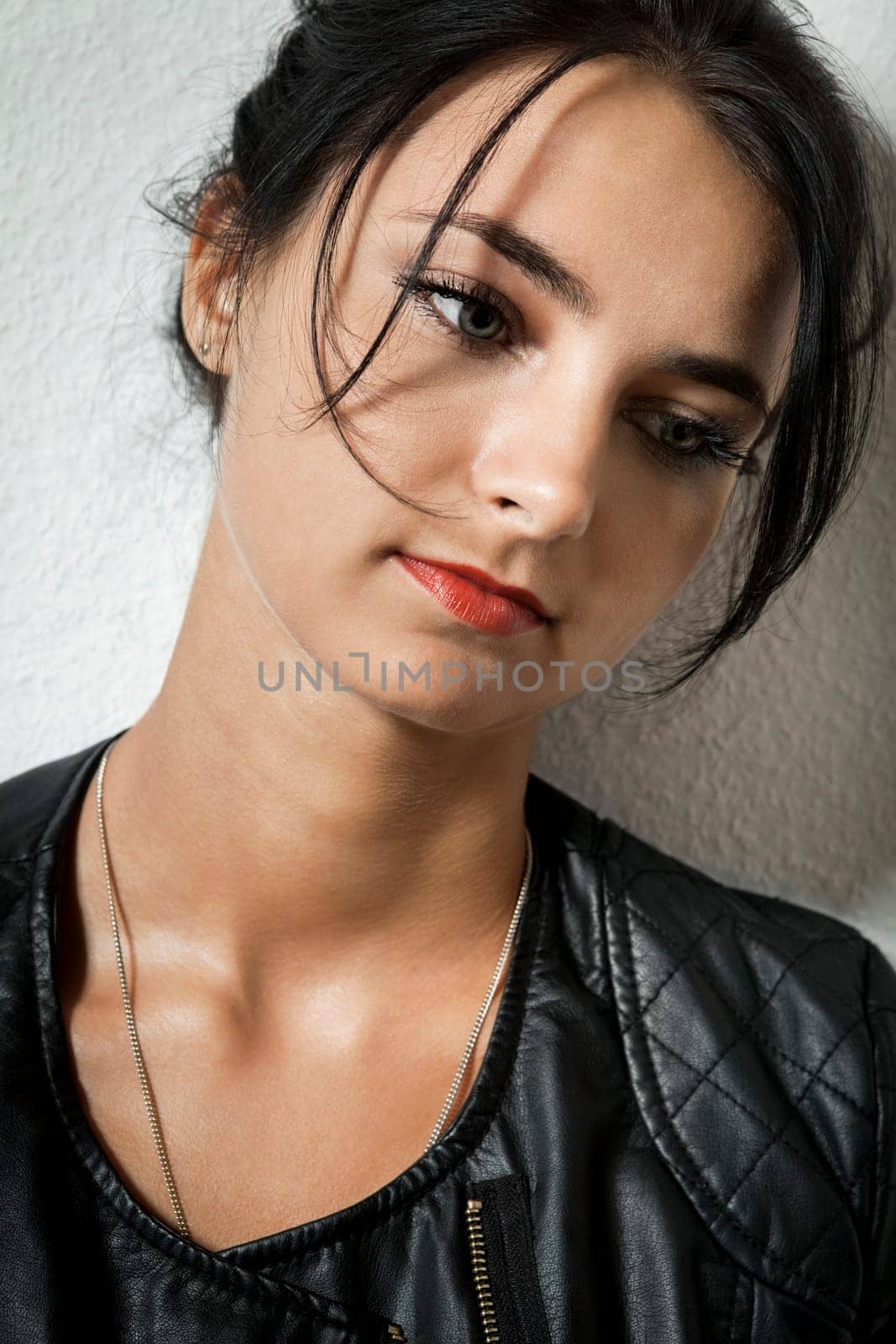 Attractive young woman with black leather jacket teases her hair against a grey background with text clearance