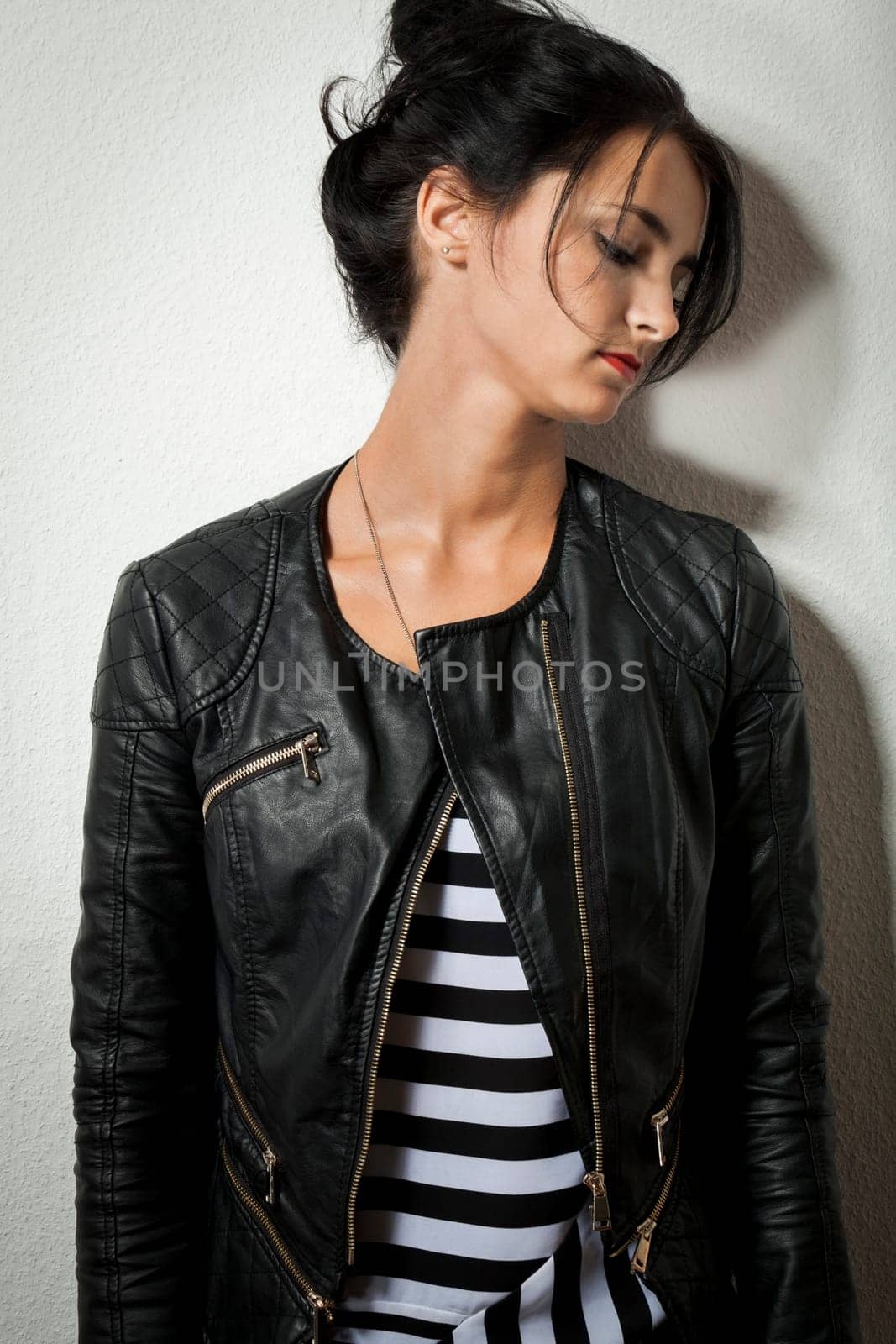 Attractive young woman with black leather jacket teases her hair against a grey background with text clearance