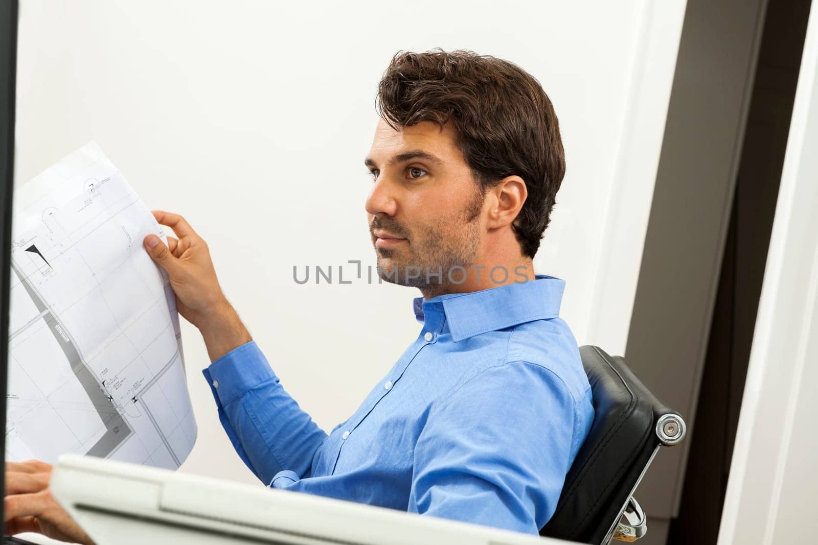 Young businessman sits with documents at a grater table in the office and informs himself