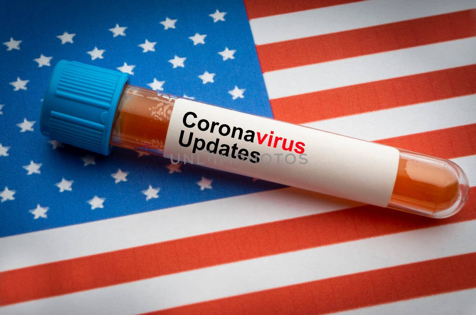 CORONAVIRUS COVID-19 UPDATE text and blood sample vacuum tube on America flags background. Covid-19 or Coronavirus Concept