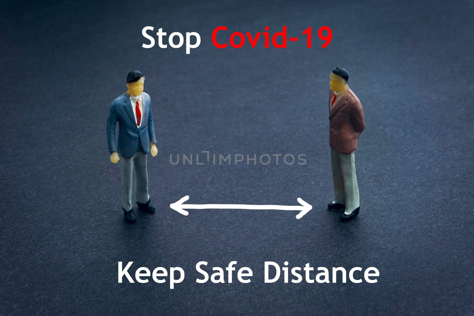 STOP COVID-19 KEEP SAFE DISTANCE text with miniature people on dark background. Covid-19 or Coronavirus concept