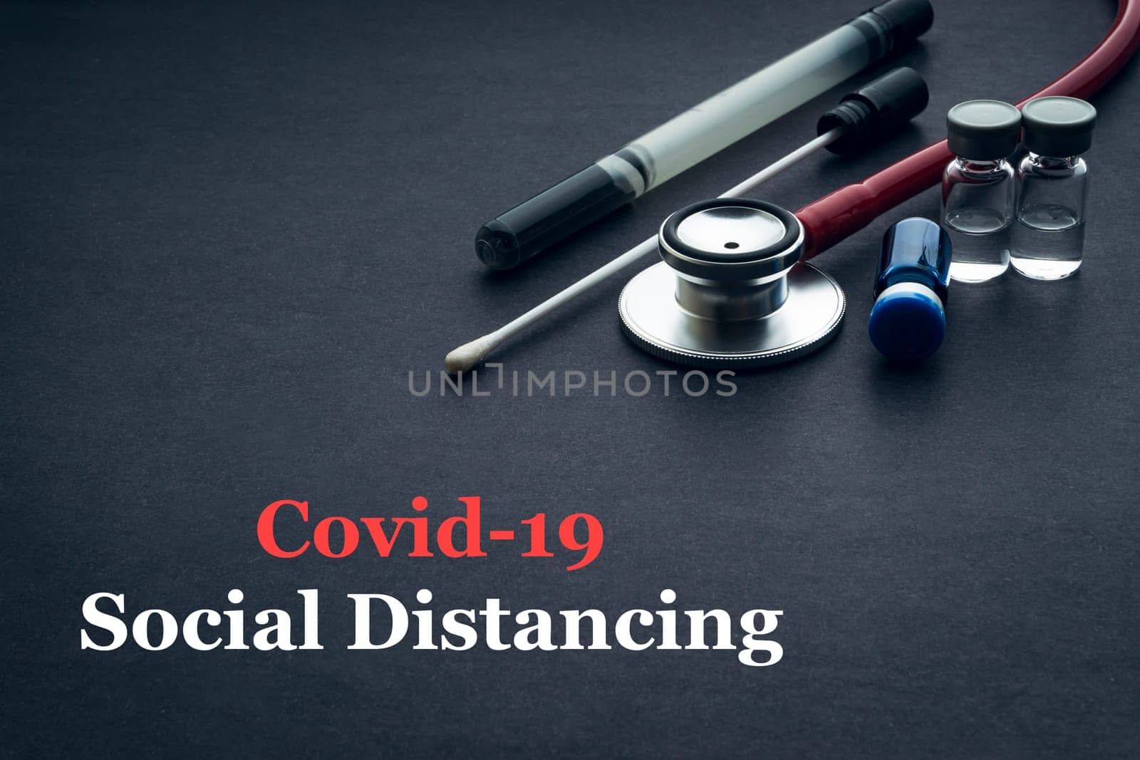 COVID-19 or CORONAVIRUS SOCIAL DISTANCING text with stethoscope, medical swab and vial on black background. Covid-19 or Coronavirus concept.
