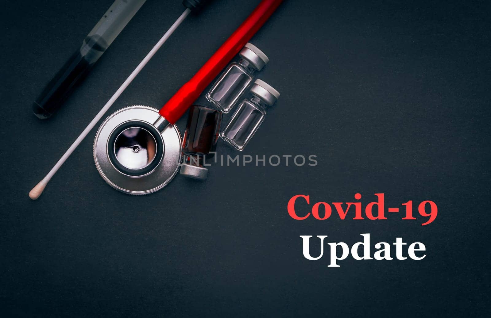 COVID-19 or CORONAVIRUS UPDATE text with stethoscope, medical swab and vial on black background. Covid-19 or Coronavirus concept.