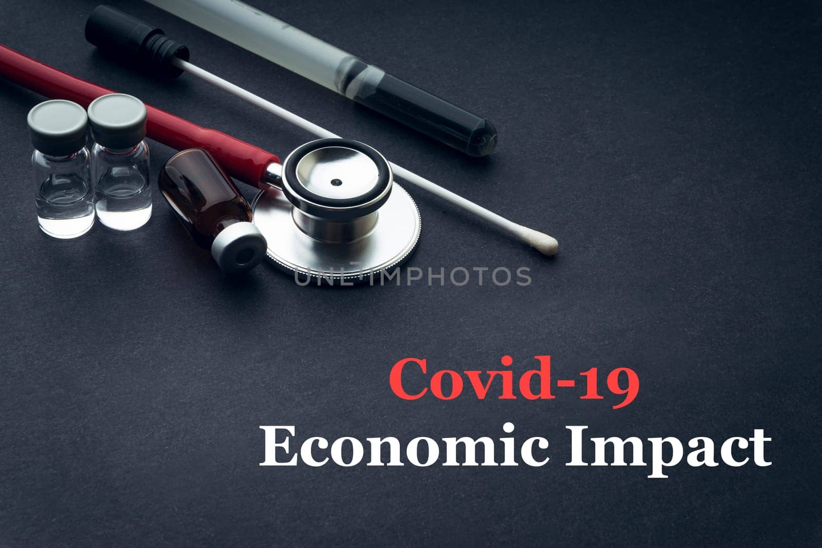 COVID-19 or CORONAVIRUS ECONOMIC IMPACT text with stethoscope, medical swab and vial on black background. Covid-19 or Coronavirus concept.