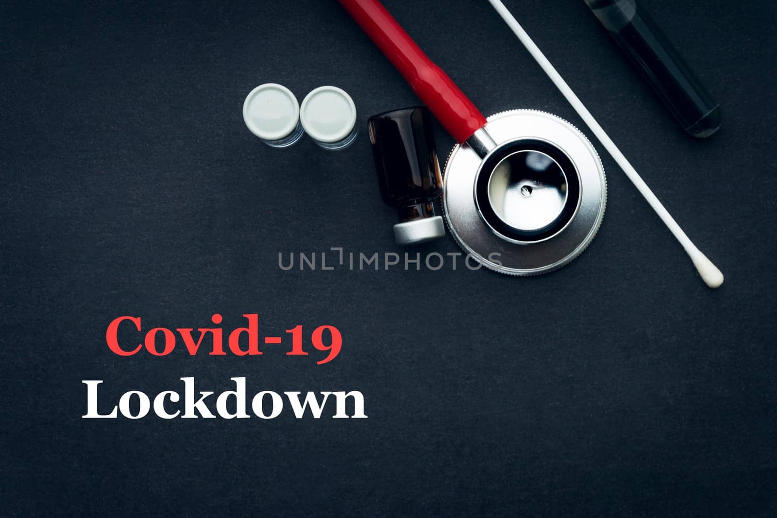 COVID-19 or CORONAVIRUS LOCKDOWN text with stethoscope, medical swab and vial on black background. Covid-19 or Coronavirus concept.
