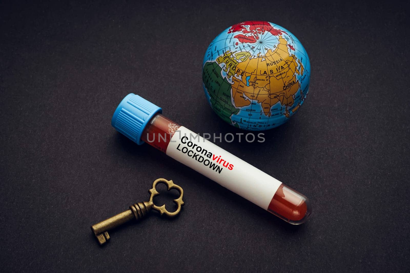 CORONAVIRUS LOCKDOWN text with world globe, key and Blood test vacuum tube on black background. Covid-19 or Coronavirus Concept