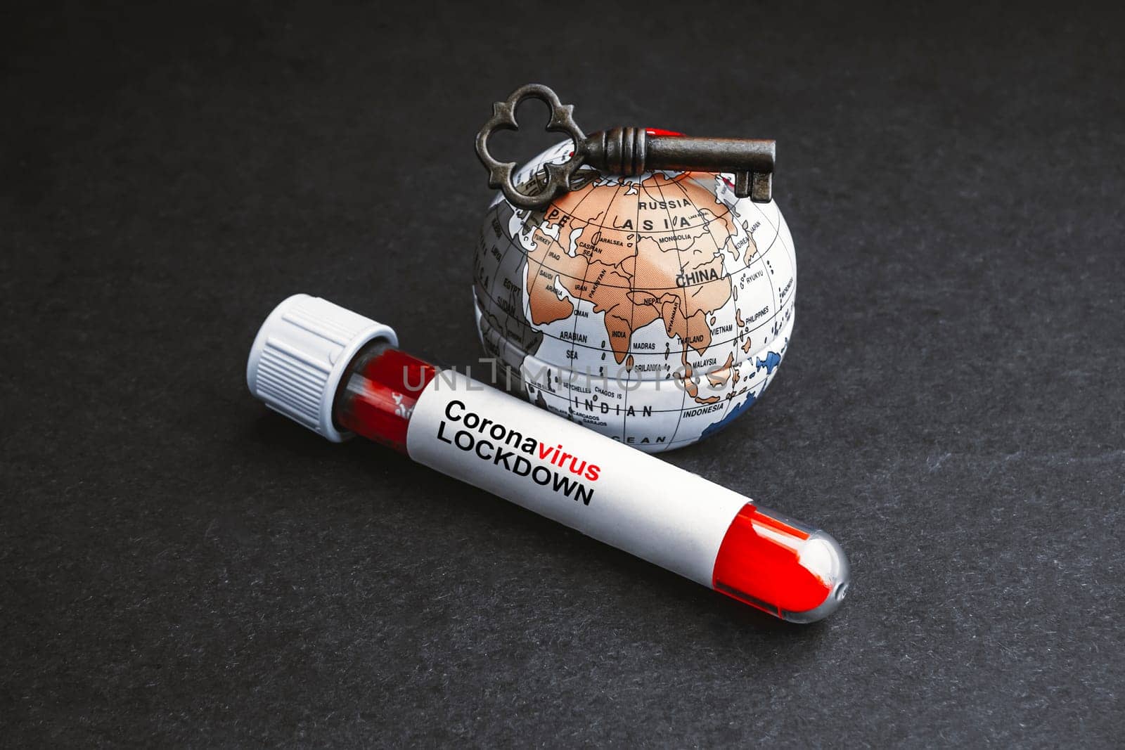 CORONAVIRUS LOCKDOWN text with world globe, key and Blood test vacuum tube on black background. Covid-19 or Coronavirus Concept