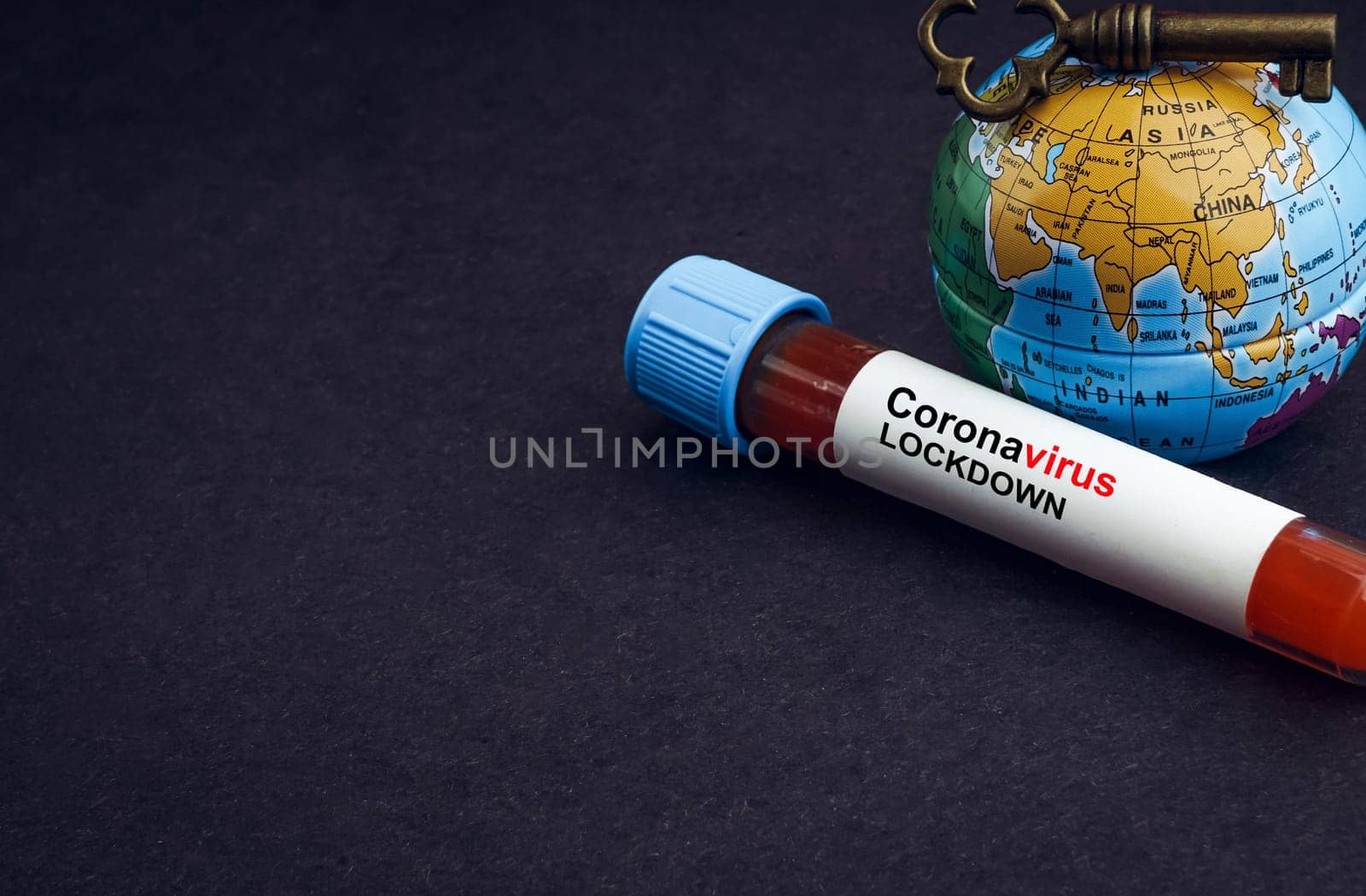 CORONAVIRUS LOCKDOWN text with world globe, key and Blood test vacuum tube on black background. Covid-19 or Coronavirus Concept