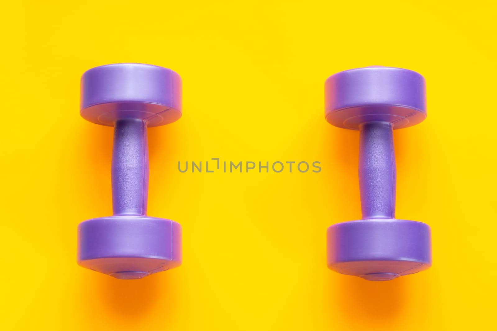 Two purple dumbbells lie separately on a yellow background
