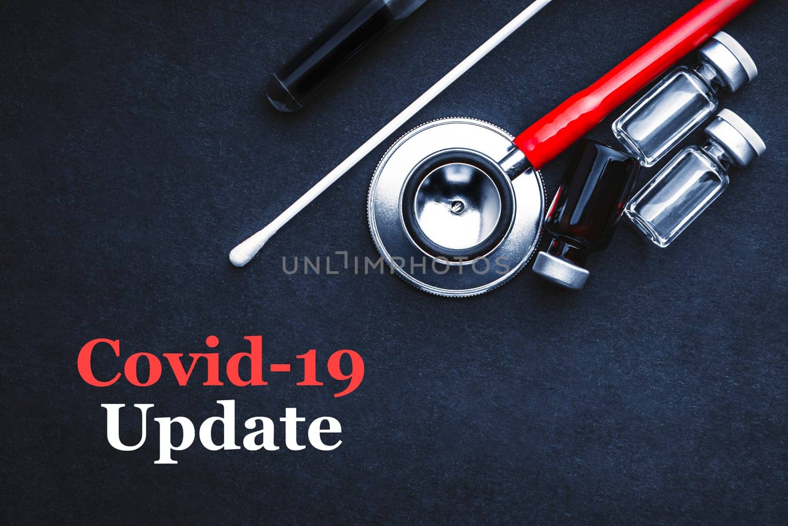 COVID-19 or CORONAVIRUS UPDATE text with stethoscope, medical swab and vial on black background. Covid-19 or Coronavirus concept.