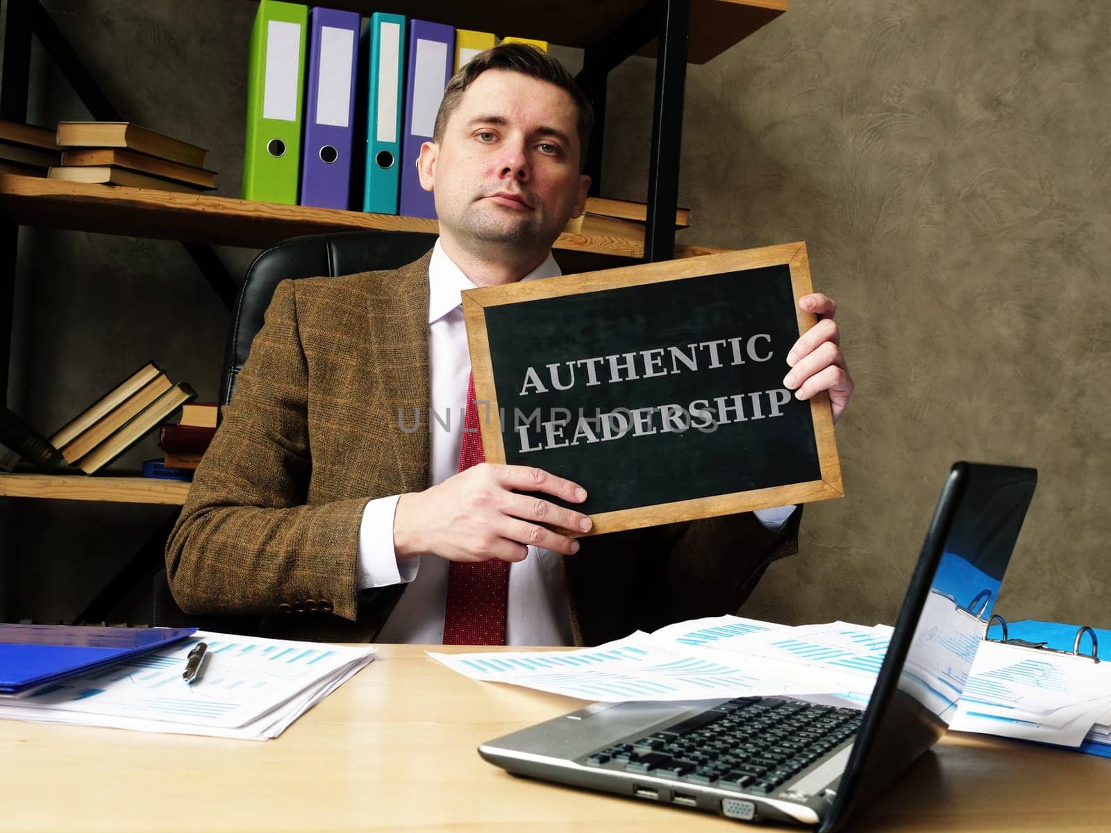 Authentic Leadership concept. Young businessman holds a black board.