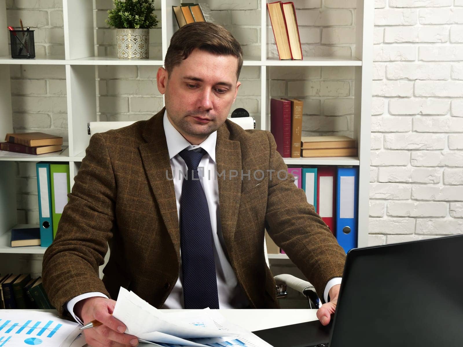 Businessman in a suit works with documents in the office. The workplace of the manager.