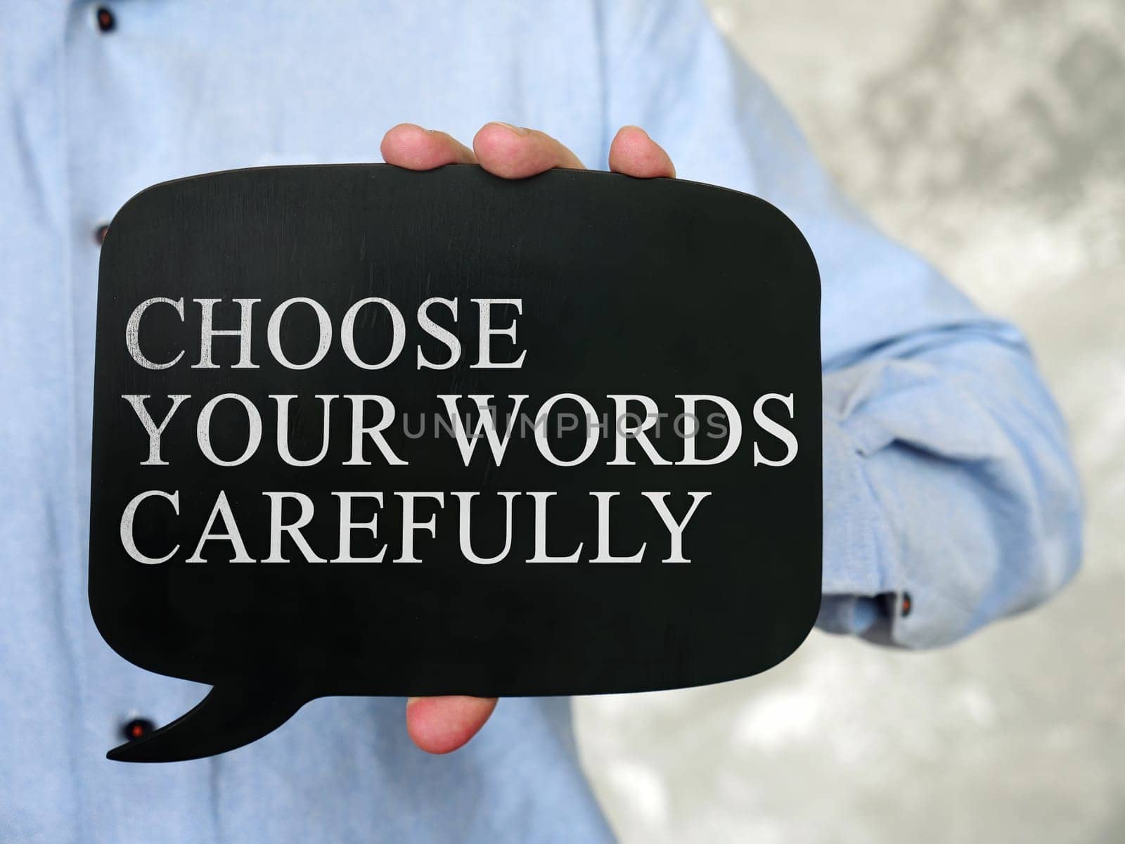 Hand holds a black tablet with the inscription Choose Your Words Carefully.