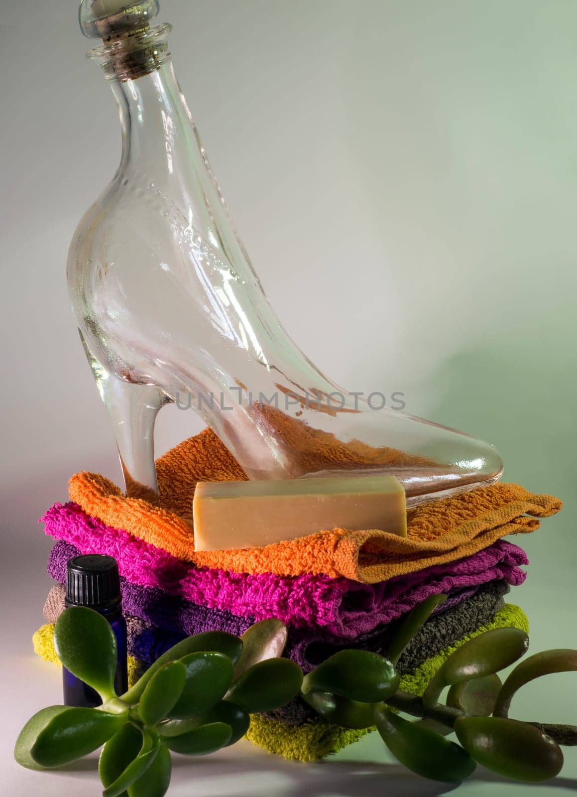 glass shoe and soap on facecloths of various shades with natural green plant