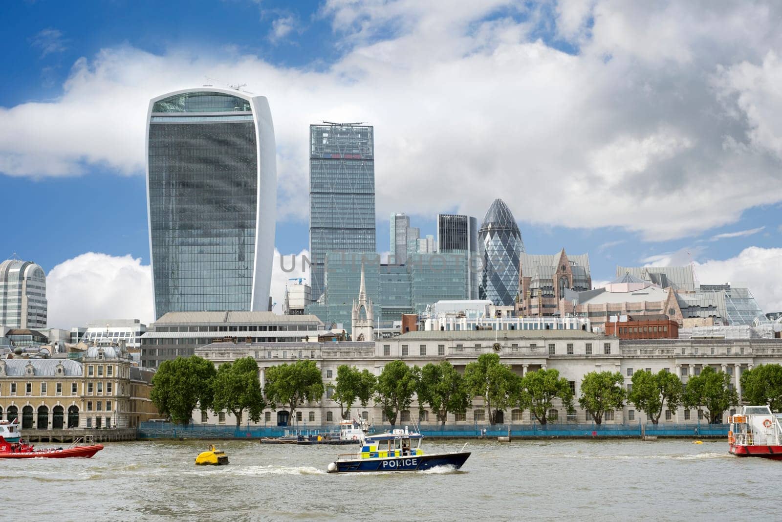 police boat on the river thames with london city skyscrapers in the background