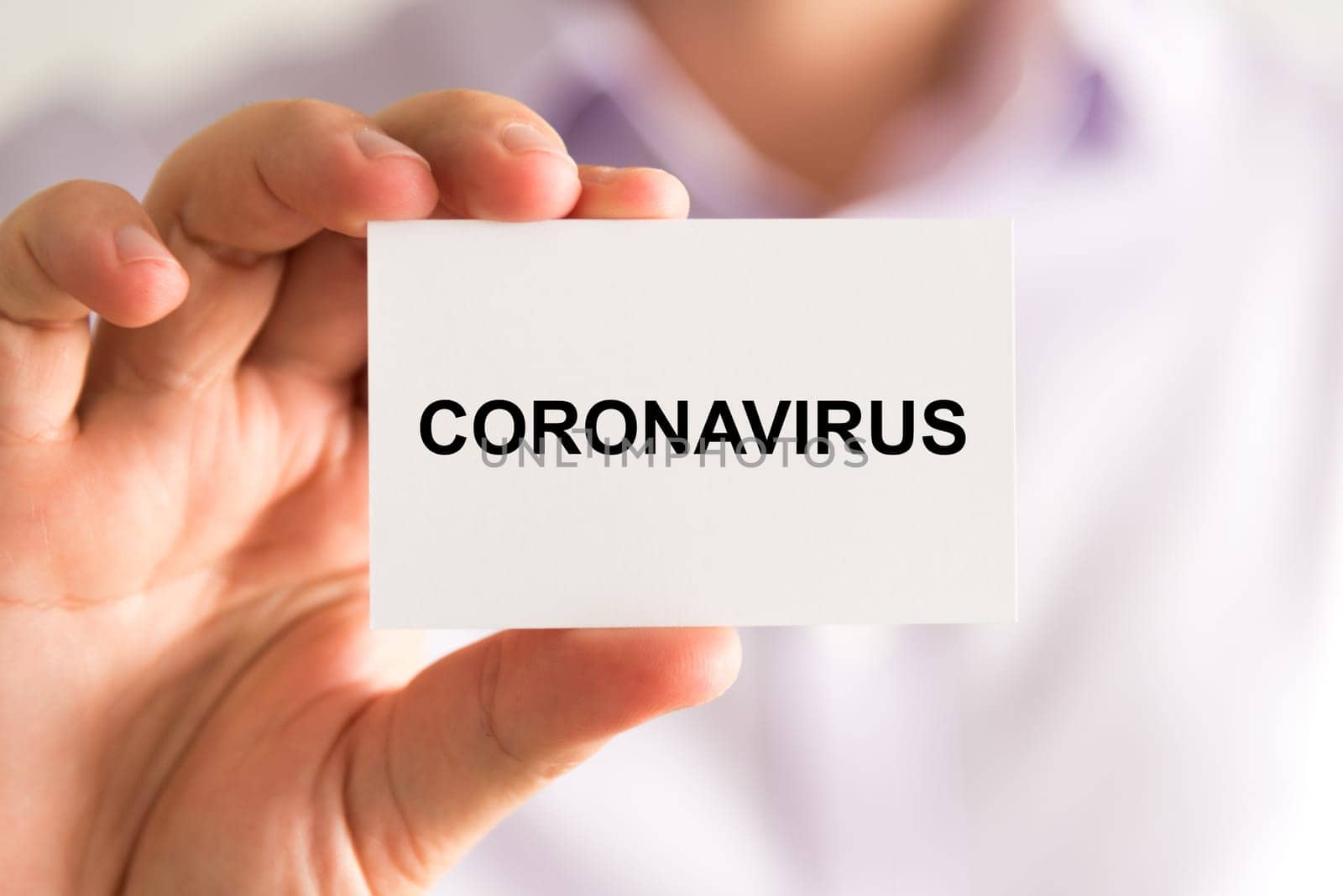 Closeup on businessman holding a card with text Coronavirus, business concept image with soft focus background