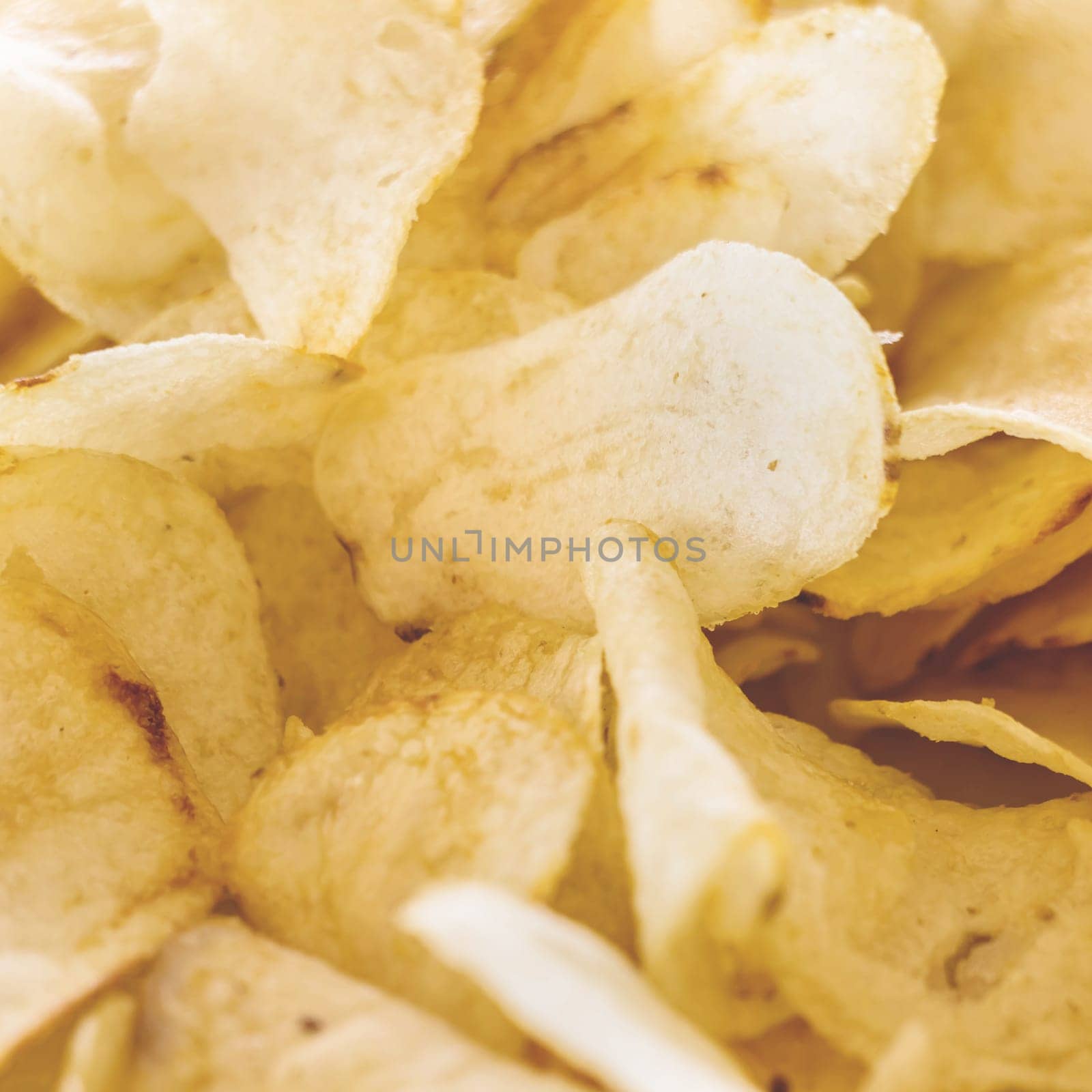 Yellow salted potato chips as background. Crispy chips golden pattern.