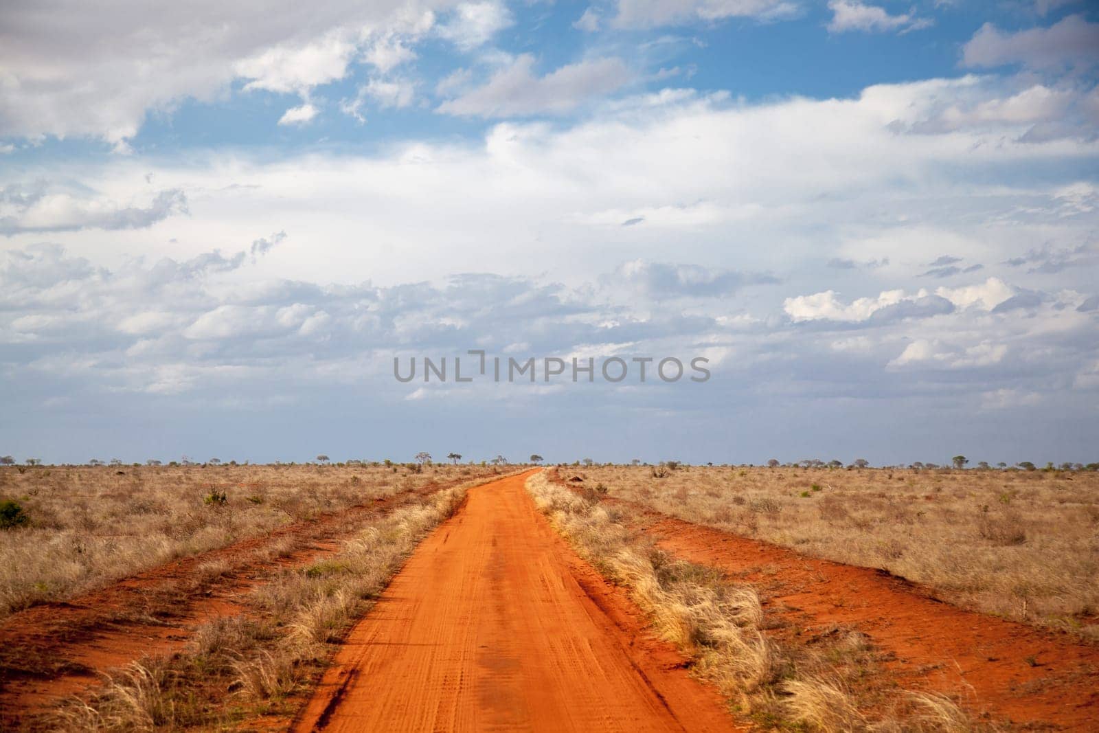 Red soil way, blue sky with clouds, scenery of Kenya.