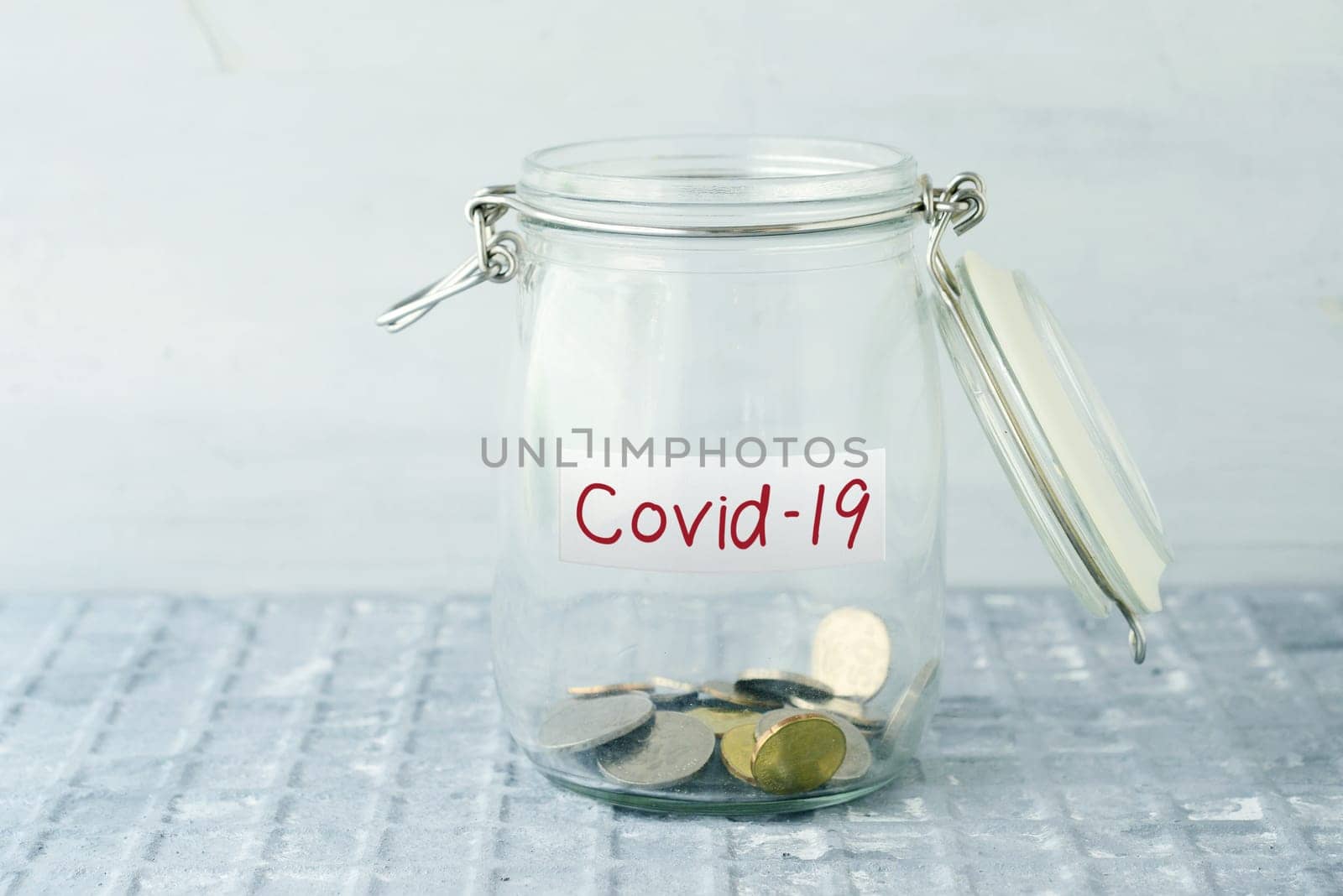 Coins in glass money jar with covid19 label, financial concept.