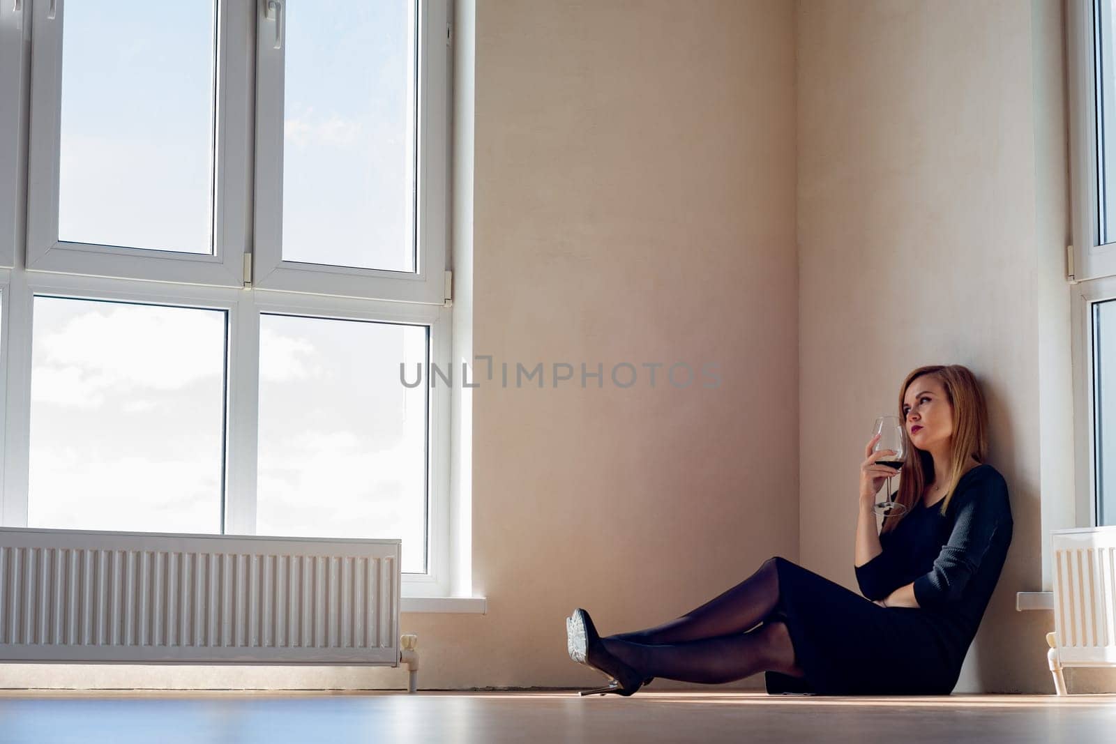 sad girl sits on the floor in an empty room with large stained glass windows