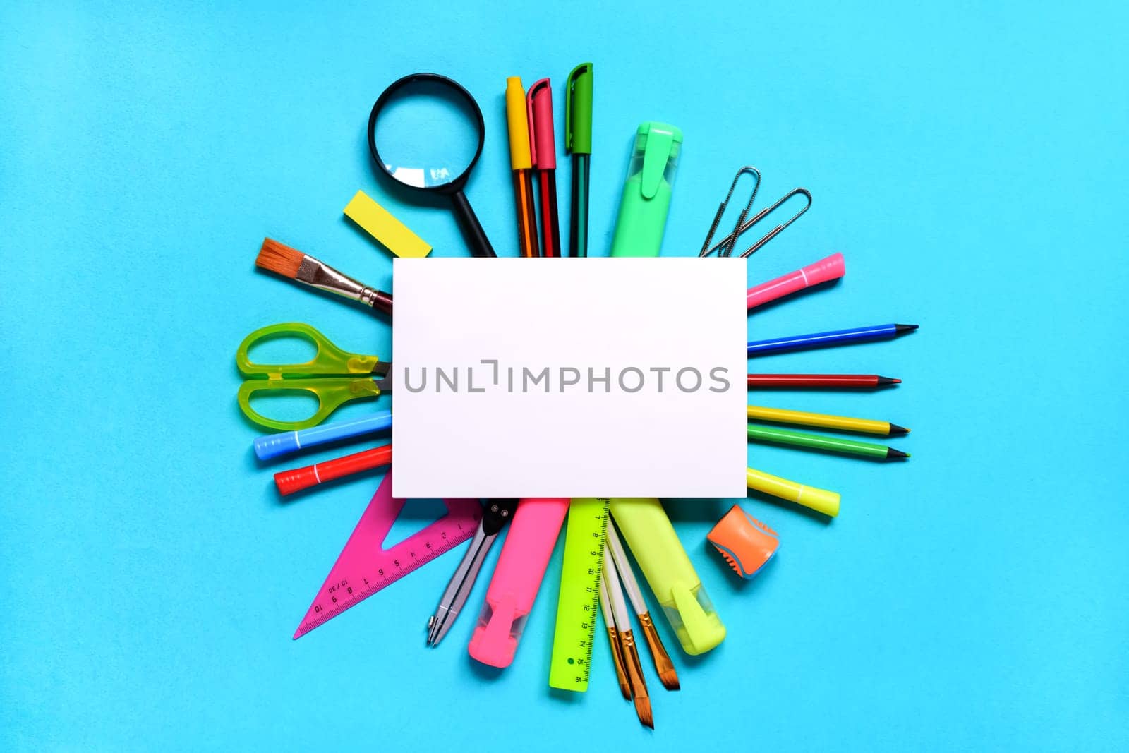 Group of School or office supplies around a notepad on light blue background. Back to school concept. Space for text. Flat lay. Mock up