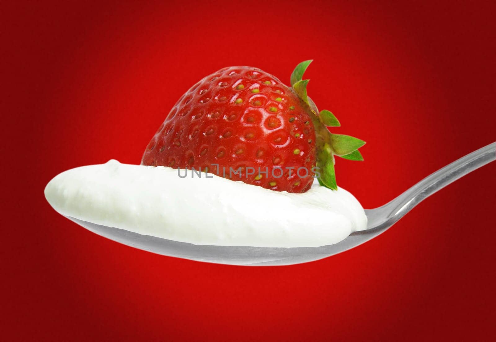 strawberry with cream on the spoon over red