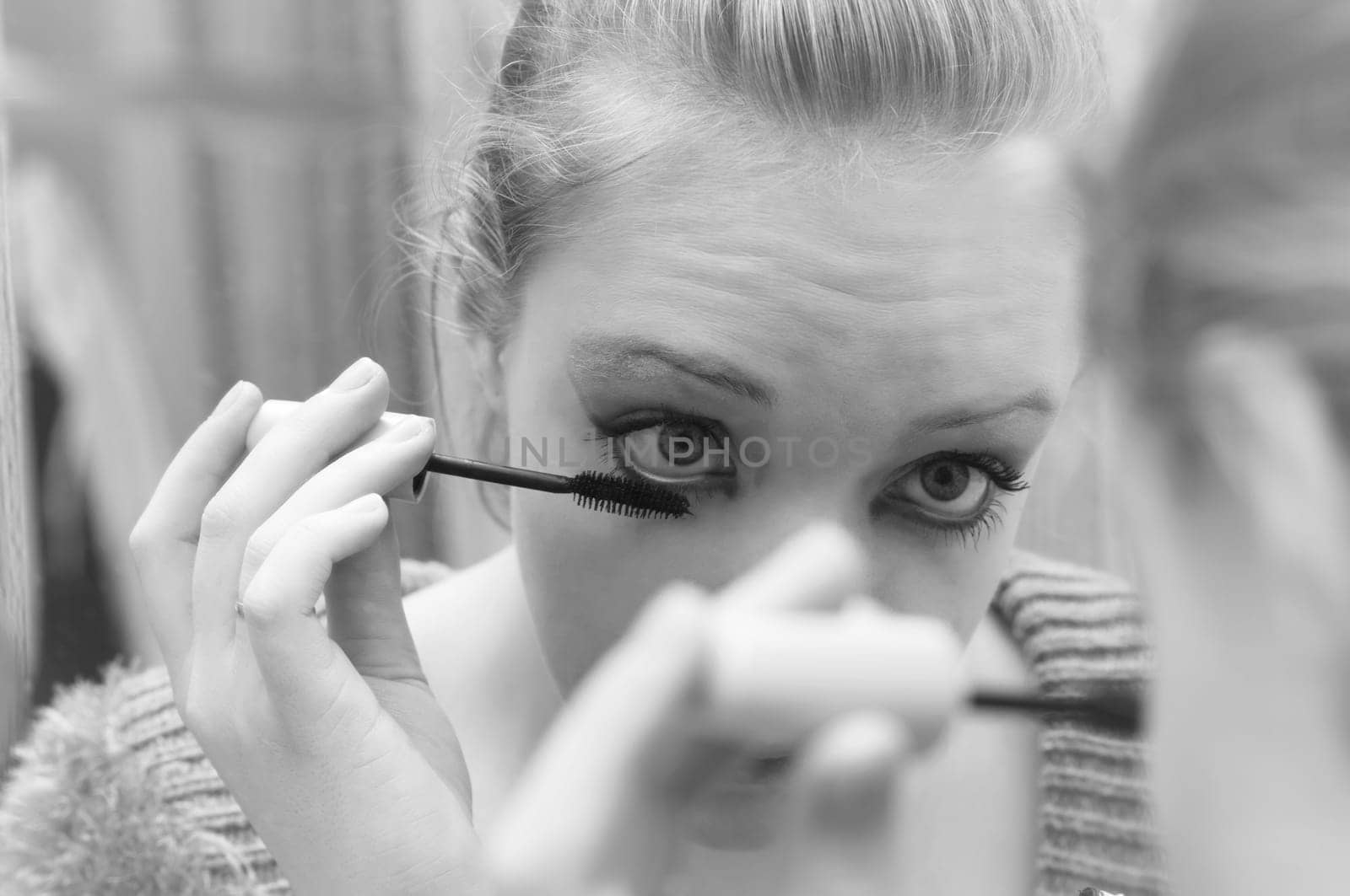woman applying make up in front of mirror.toned picture