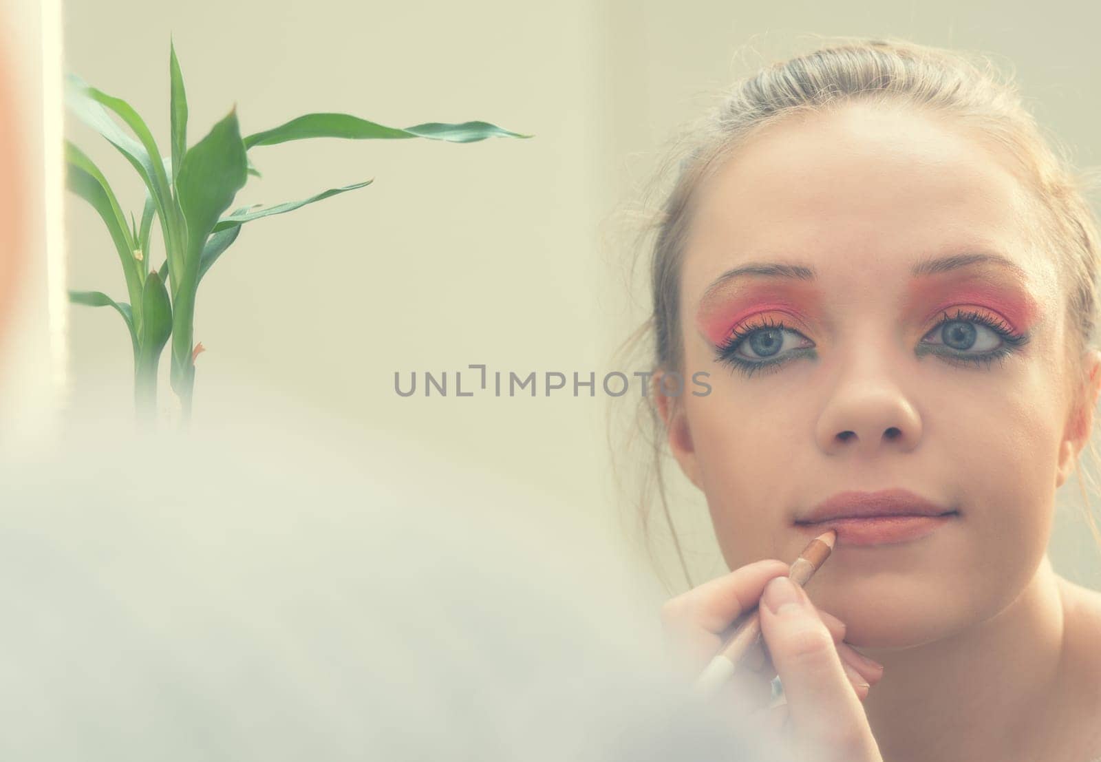 woman applying make up in front of mirror