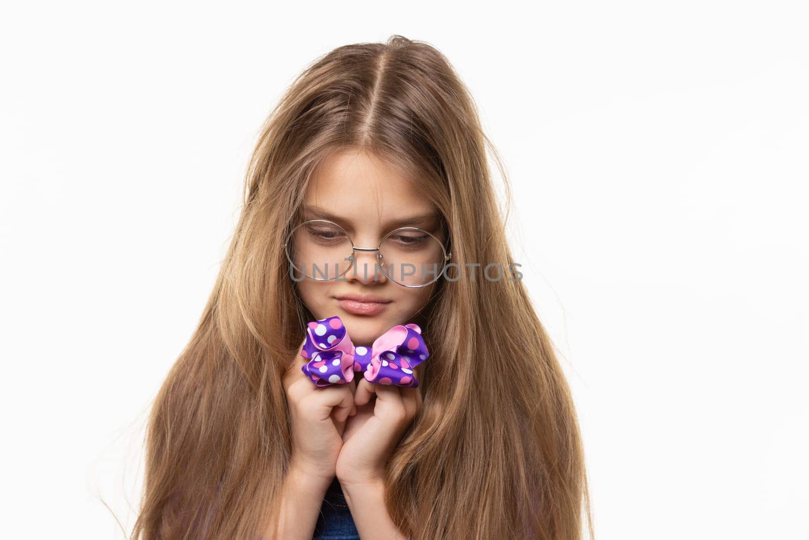 Girl sadly looks at the blue bow in her hands.