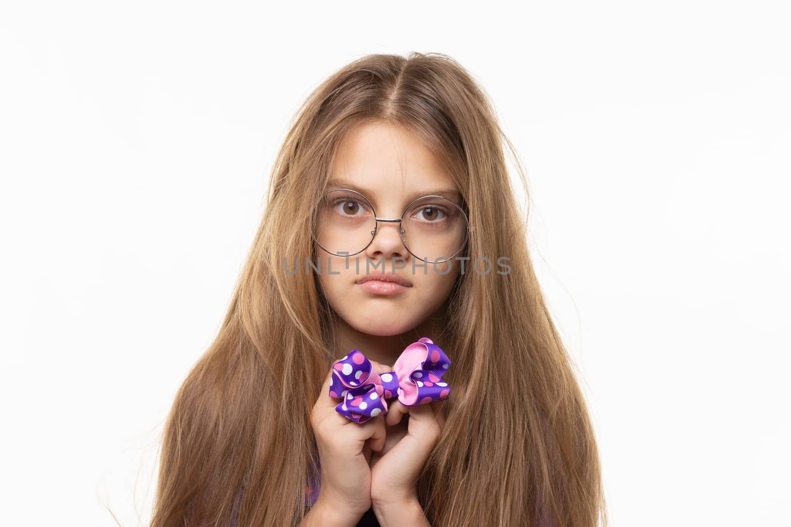 Closeup portrait of a scared girl with a blue bow in her hands