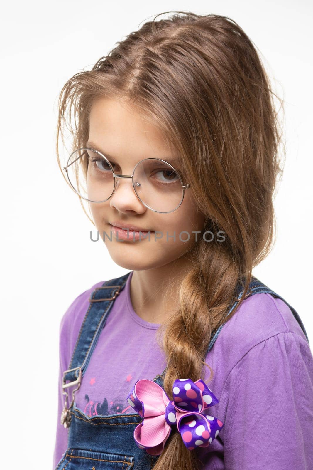 Portrait of a girl of eleven in round glasses and a long braid