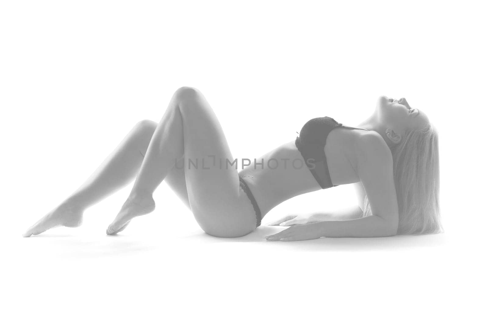 A young blonde woman in black underwear is lying on the floor