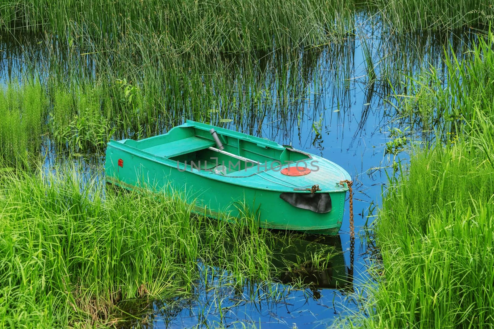Old metal rowboat moored on the lake