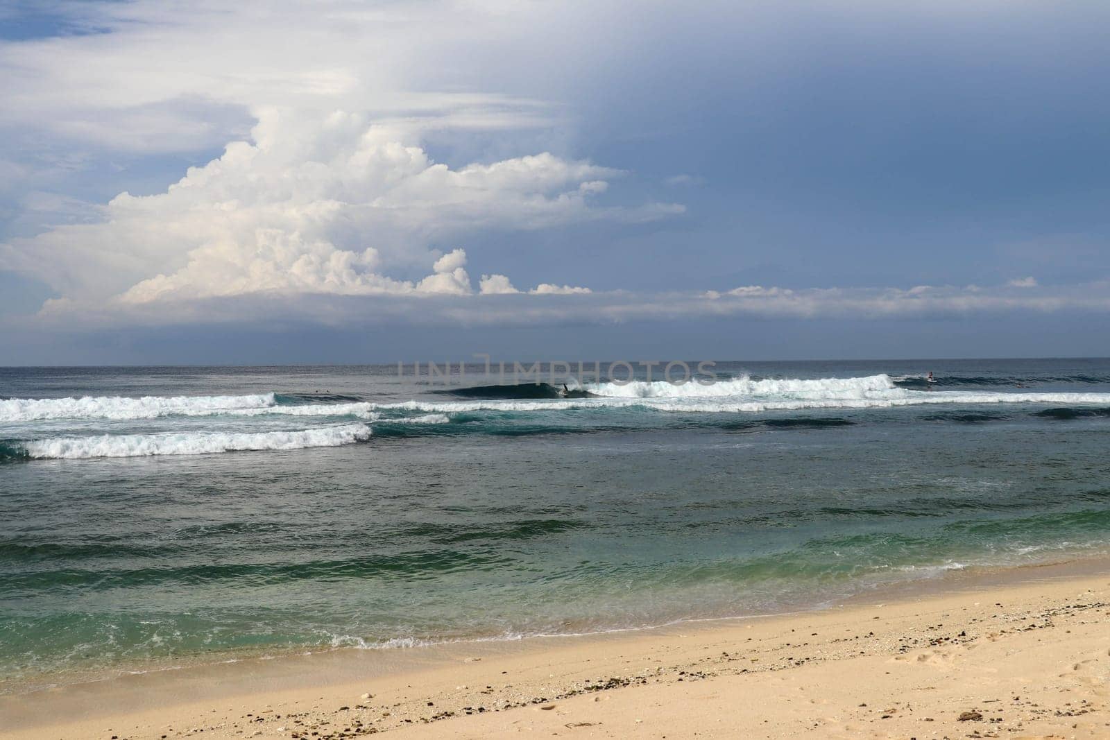 Virgin beach with fine yellow sand on Bali island. Lonely tropical paradise with Nyang Nyang beach. Azure blue sky, sunny day. Wild waves are approaching the shore in rows. Sea foam in rolling waves.
