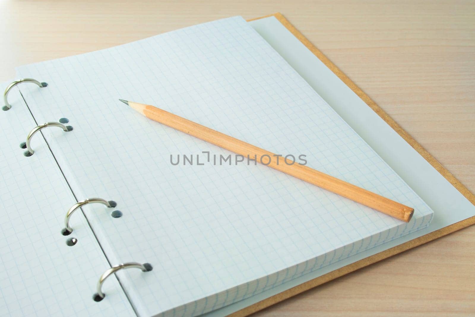 Pencil with open clear notepad on wooden table.