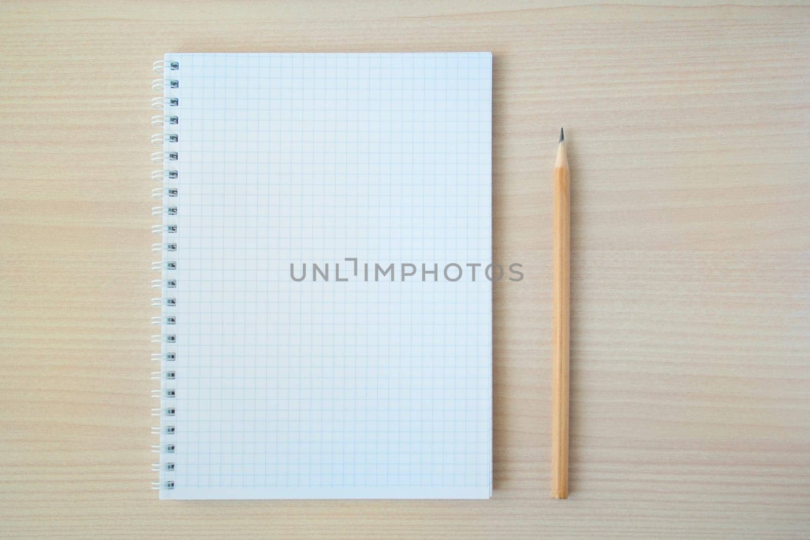 Pencil with open clear notepad on wooden table.