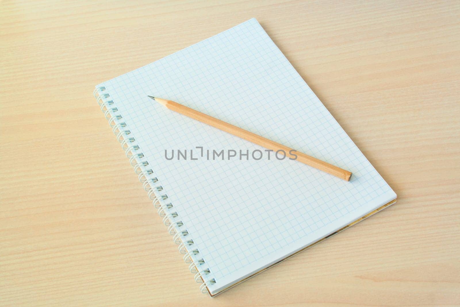 Pencil with open clear notepad on wooden table.