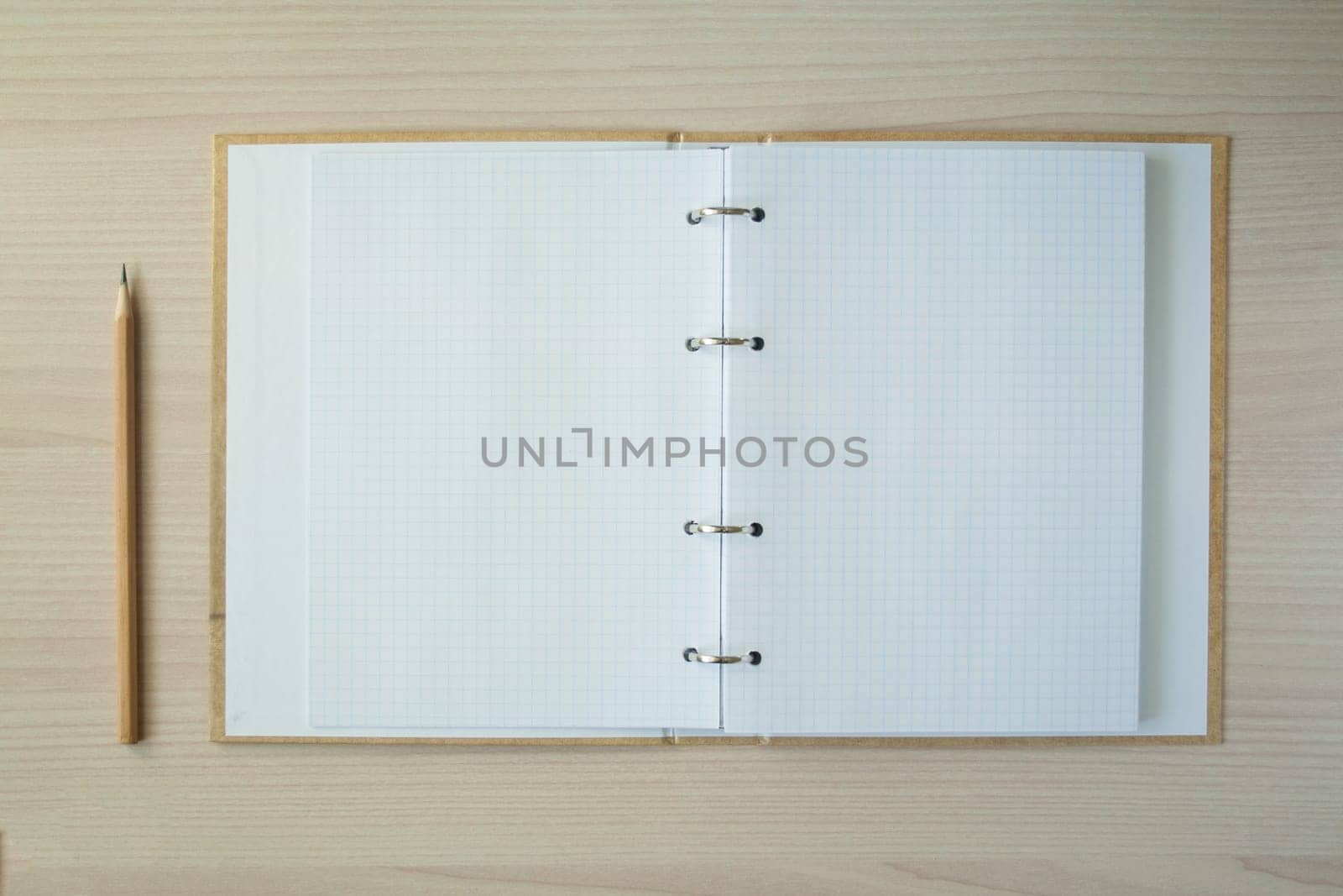 Pencil with open clear notepad on wooden table.