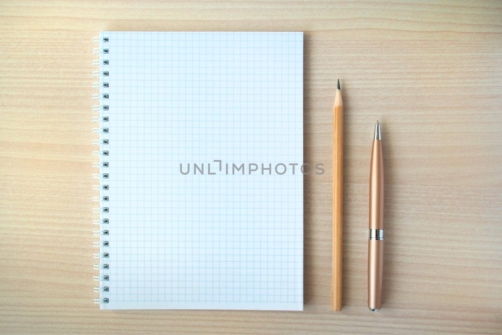 Pencil and pen with open clear notepad on wooden table, copyspace.