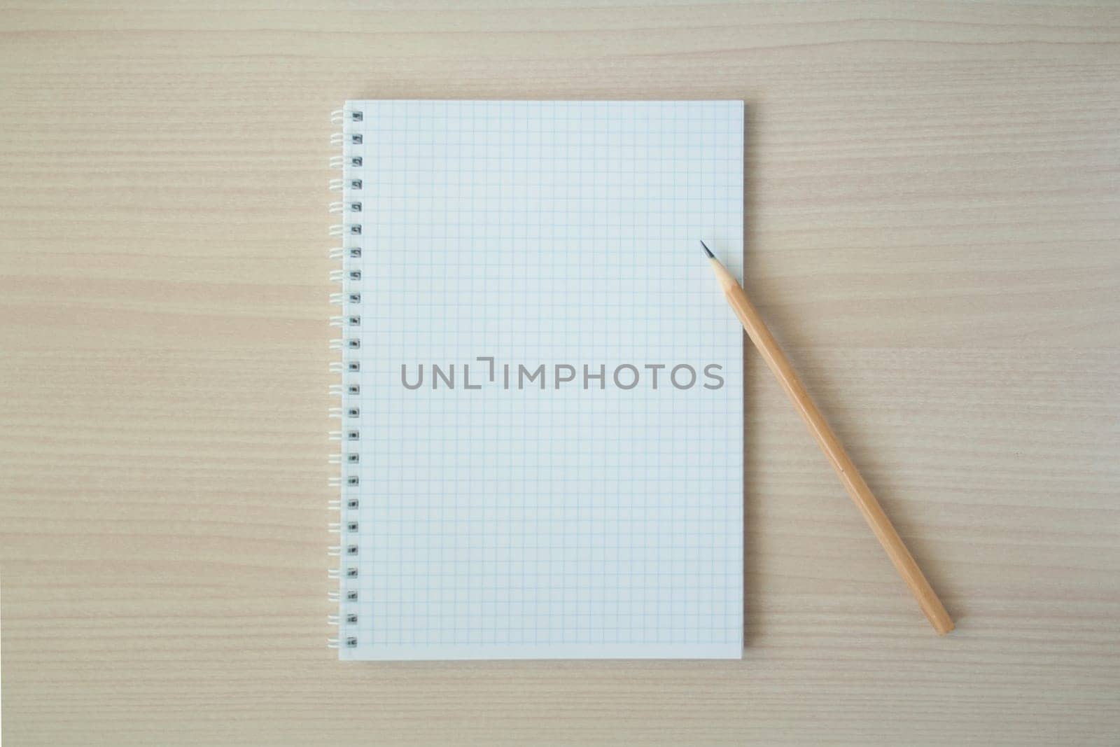 Pencil with open clear notepad on wooden table.