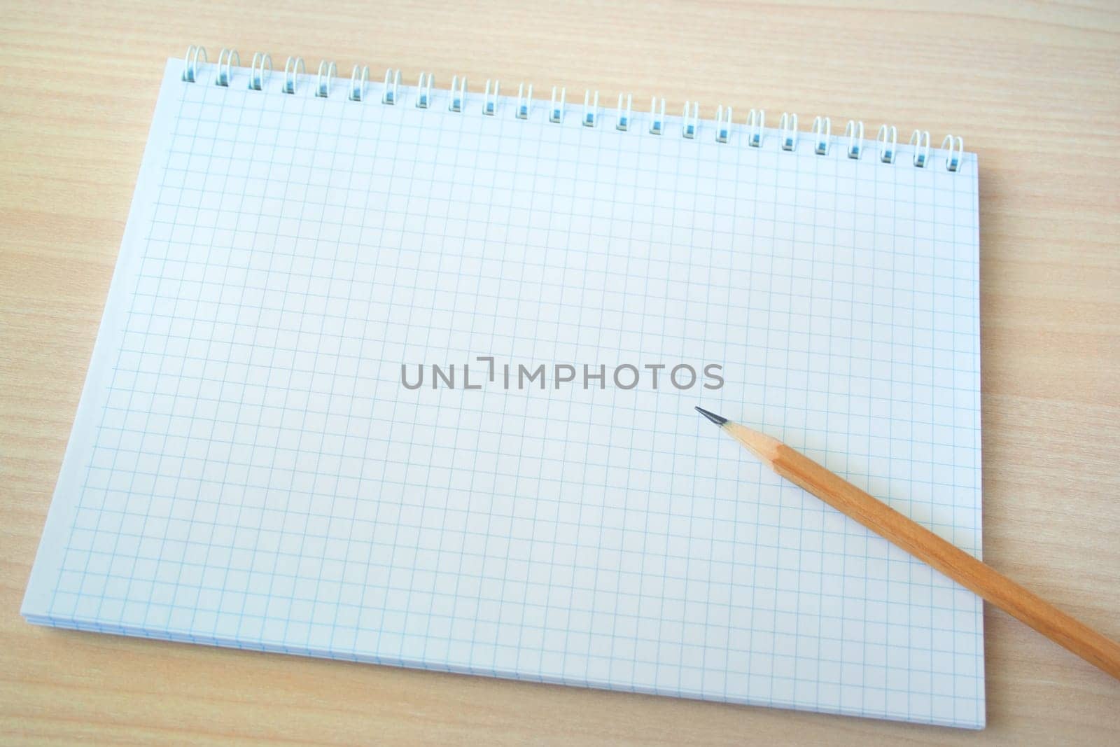 Pencil with open clear notepad on wooden table.