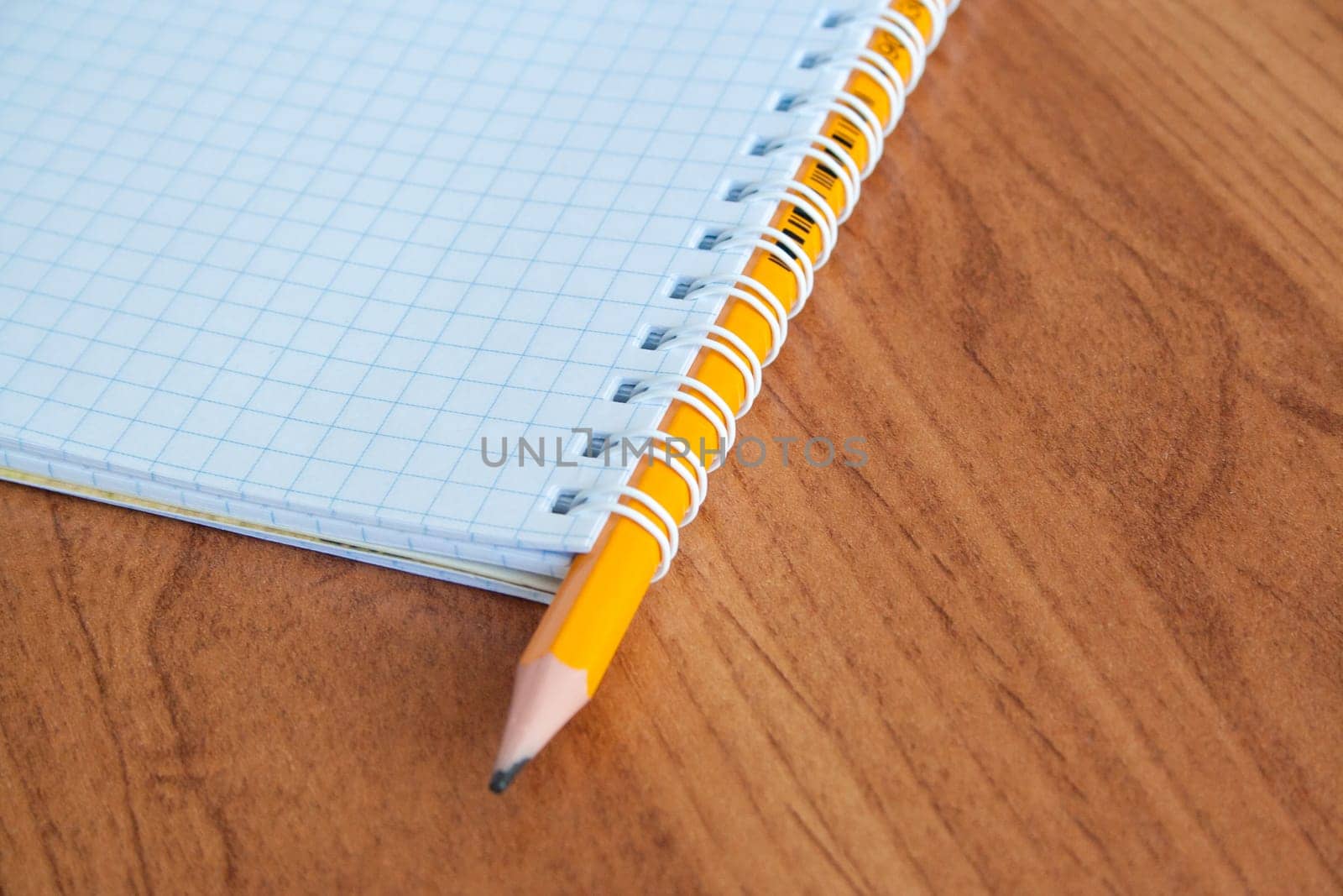 Pencil with open clear notepad on wooden table.