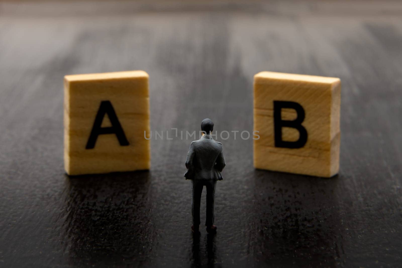 Miniature figurine posed as businessman making decision on Solution A versus B, minimalist abstract concept image