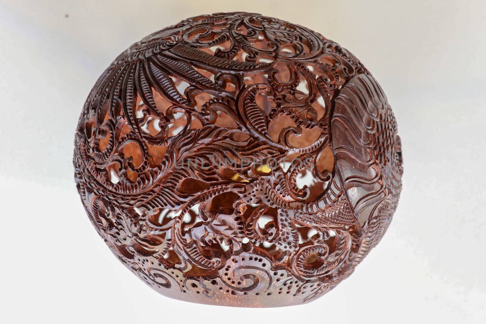 Close up ornamental shell for candle. Carved Souvenir from Coconut. Traditional handicraft on Bali, Indonesia. Hand carved ornaments with animal and plant motifs on the coconut shell. Mystical dragon.